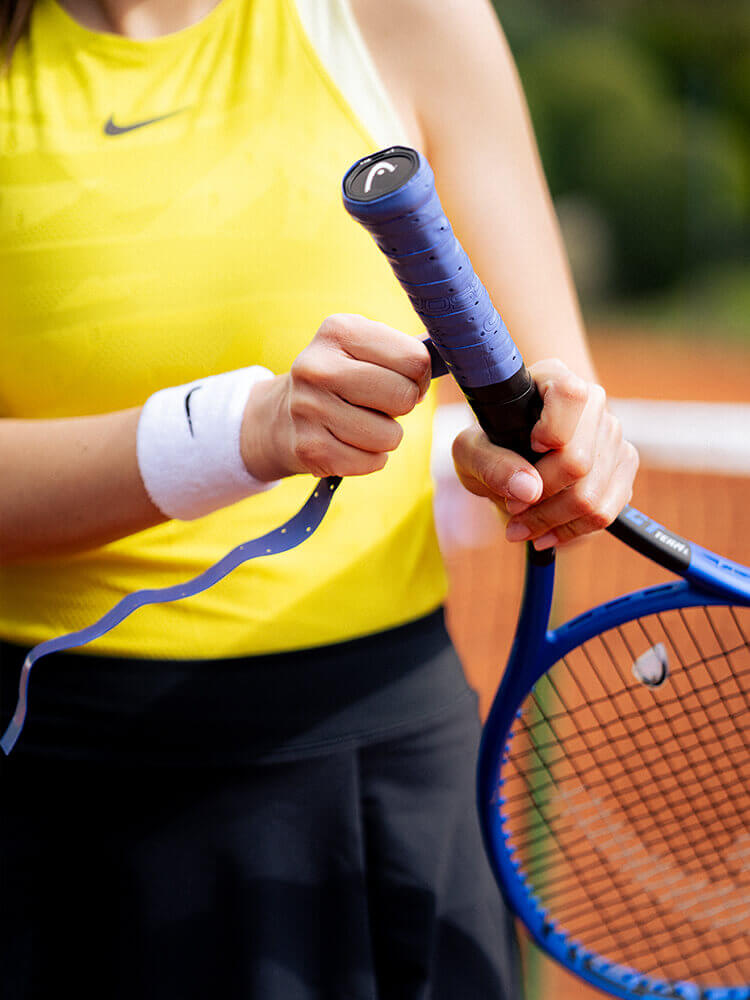 Ragazza che mette il nastro sulla racchetta da tennis